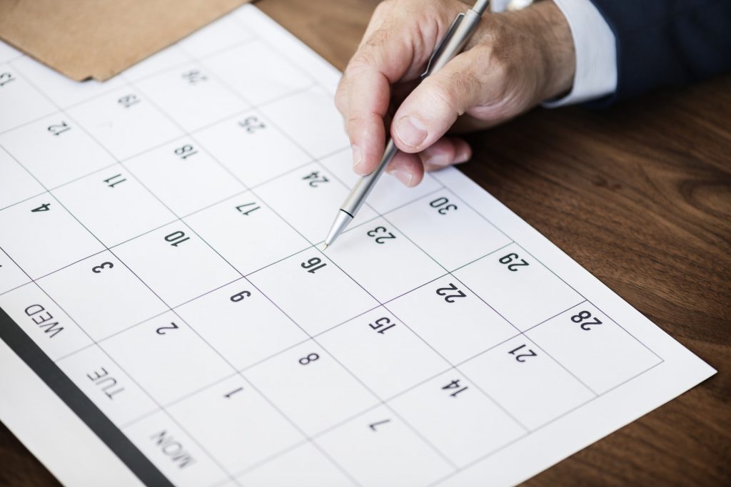 A hand holding a digital pen showing dates on the calendar